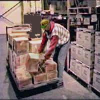 OSHA hazard example: a selector leaning across a pallet while holding a case.